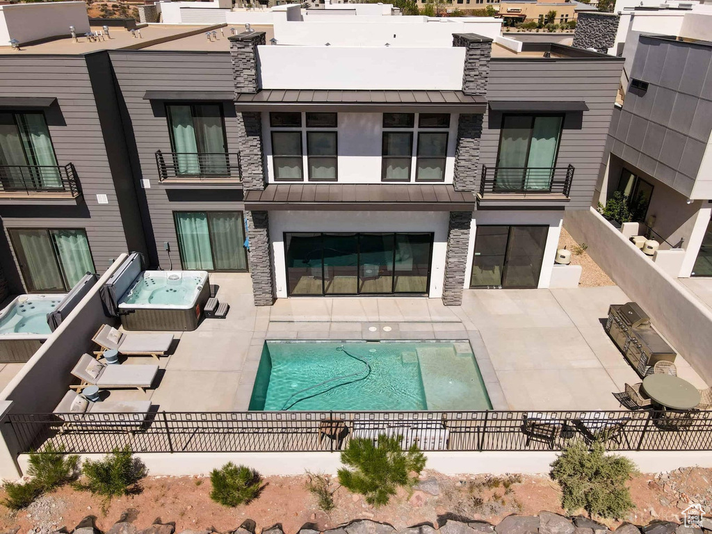 Back of property featuring a patio area, a balcony, and a fenced in pool