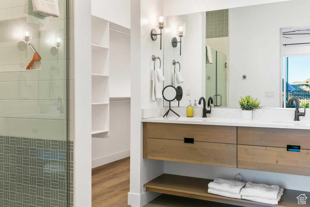 Bathroom featuring double vanity, a shower with shower door, and hardwood / wood-style flooring