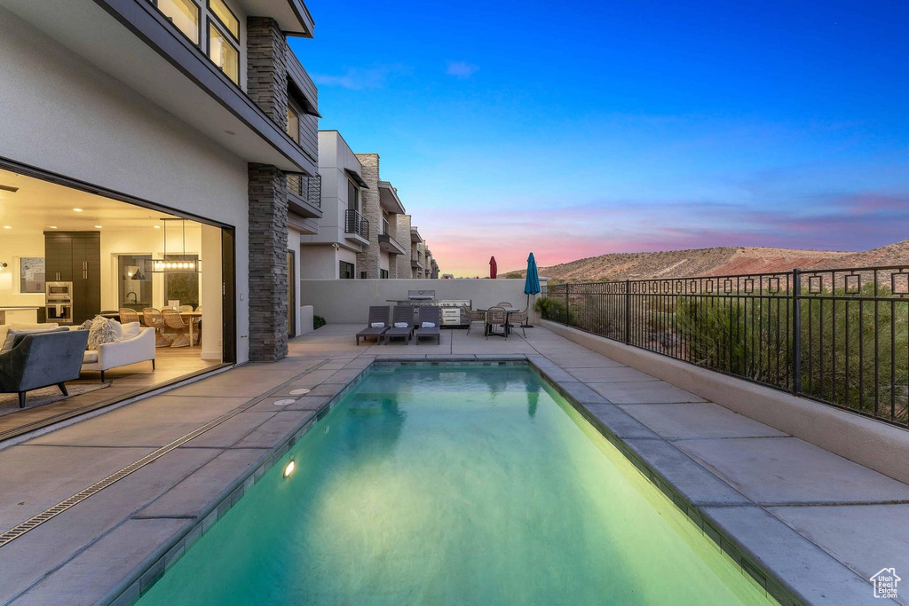 Pool at dusk with area for grilling, an outdoor hangout area, and a patio area
