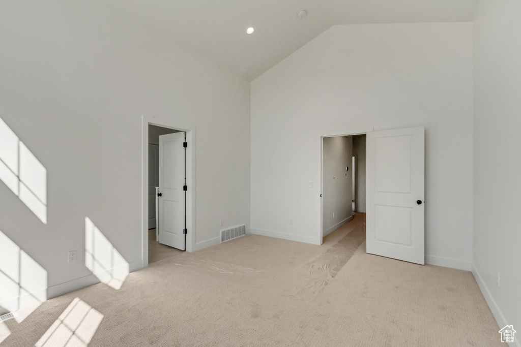 Unfurnished room featuring high vaulted ceiling and light carpet