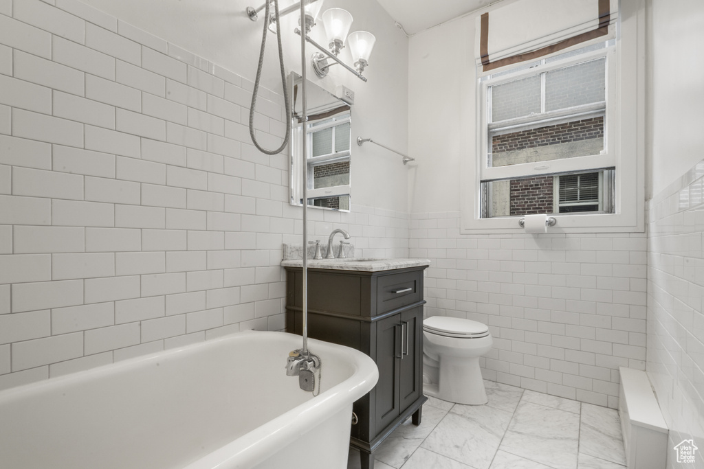 Bathroom featuring vanity, toilet, tile flooring, and tile walls