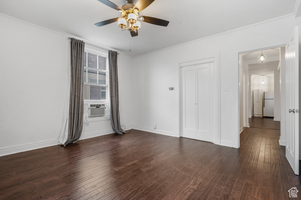 Spare room with ceiling fan, dark wood-type flooring, and crown molding