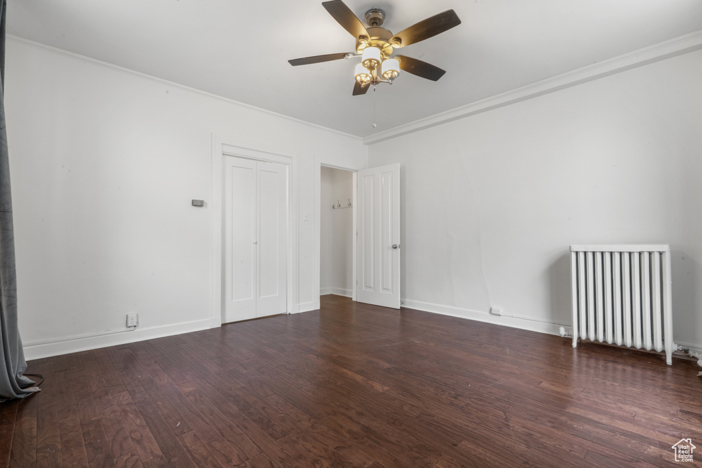 Spare room featuring crown molding, radiator, ceiling fan, and dark hardwood / wood-style floors