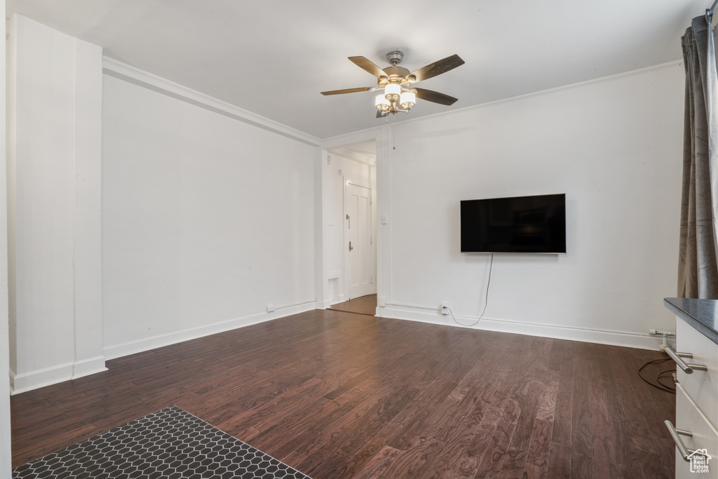 Unfurnished living room featuring ornamental molding, ceiling fan, and dark hardwood / wood-style floors