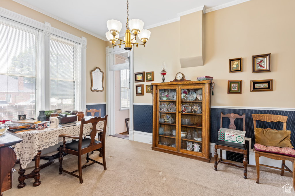 Dining space with light colored carpet, crown molding, and a chandelier
