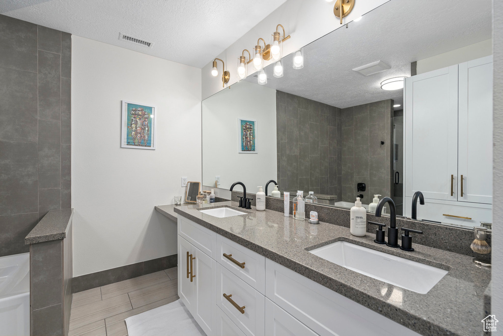Bathroom with tile flooring, double vanity, and a textured ceiling