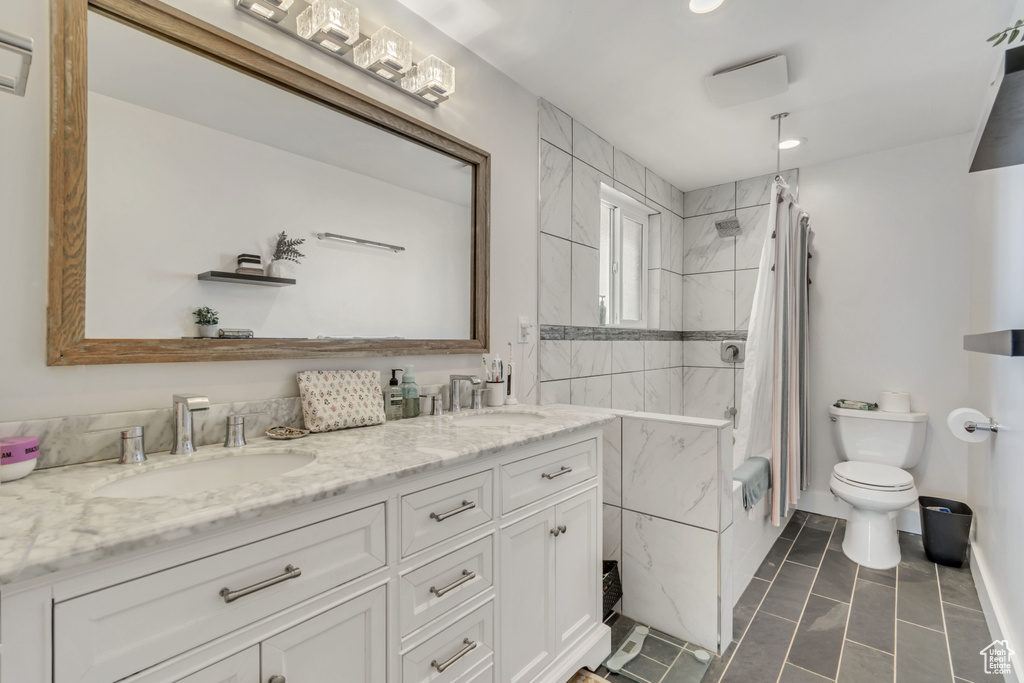 Full bathroom featuring oversized vanity, shower / tub combo, toilet, tile floors, and dual sinks