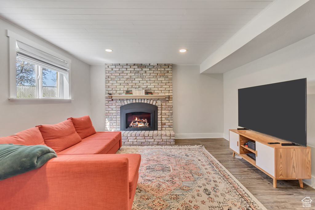 Living room with brick wall, a brick fireplace, and dark wood-type flooring