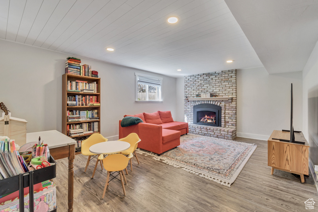 Living room featuring a fireplace, light hardwood / wood-style floors, and brick wall