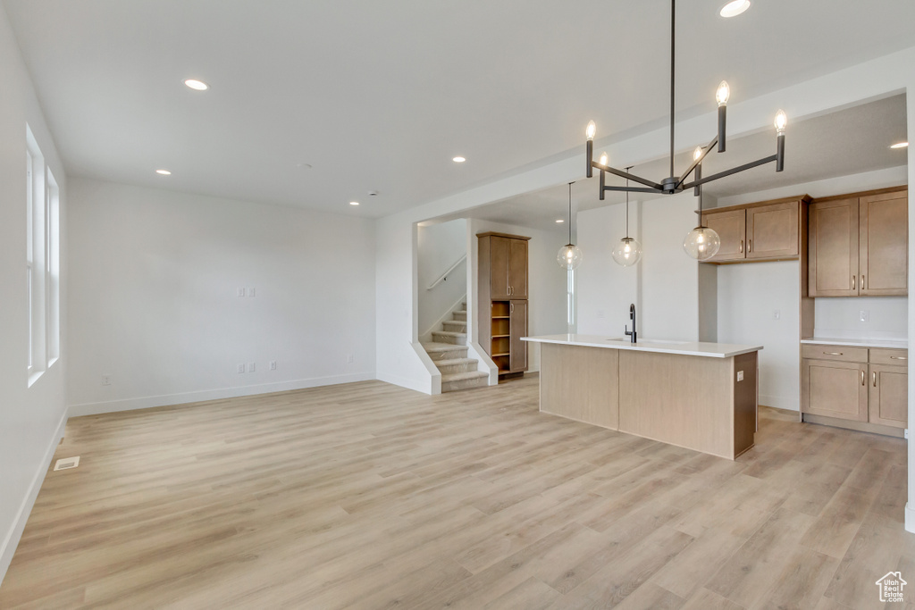 Kitchen featuring hanging light fixtures, sink, a center island with sink, and light hardwood / wood-style floors
