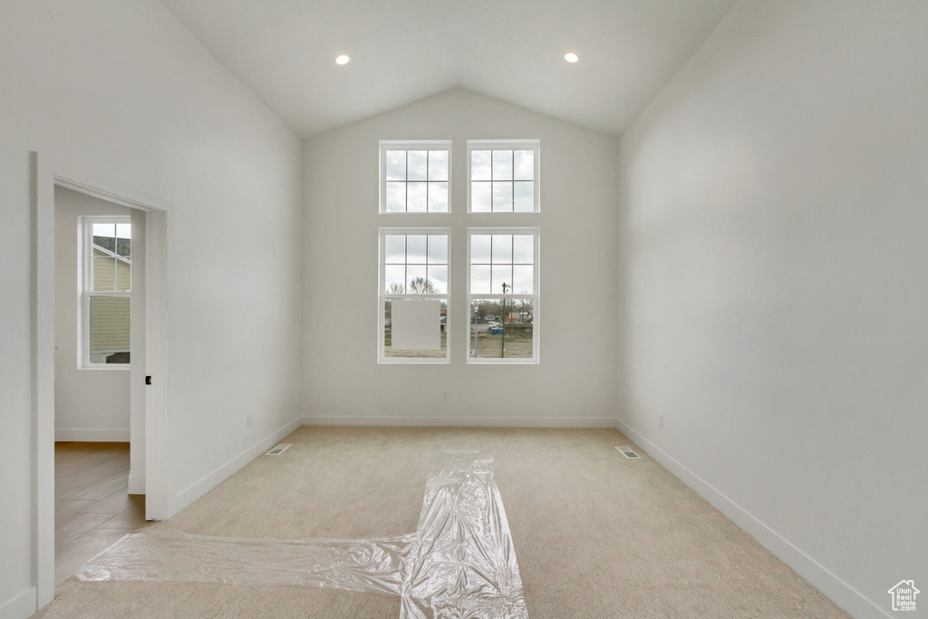 Unfurnished room with light carpet and lofted ceiling