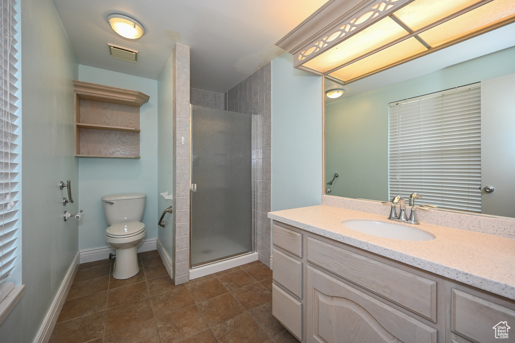 Bathroom featuring a shower with door, toilet, tile flooring, and vanity