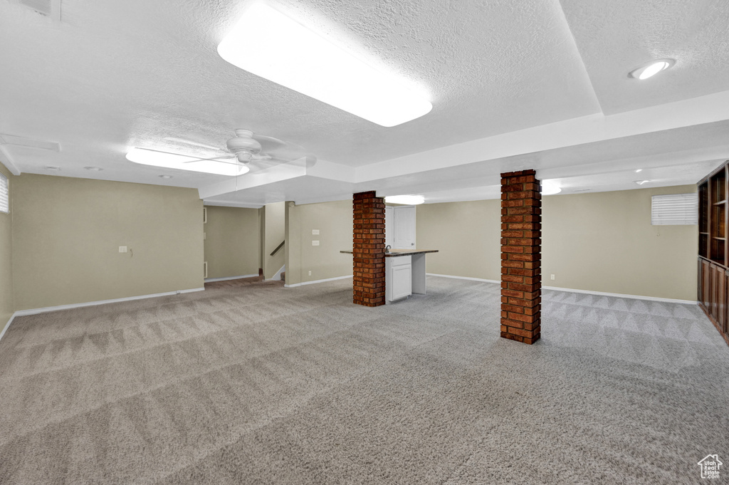 Basement featuring brick wall, light colored carpet, and a textured ceiling