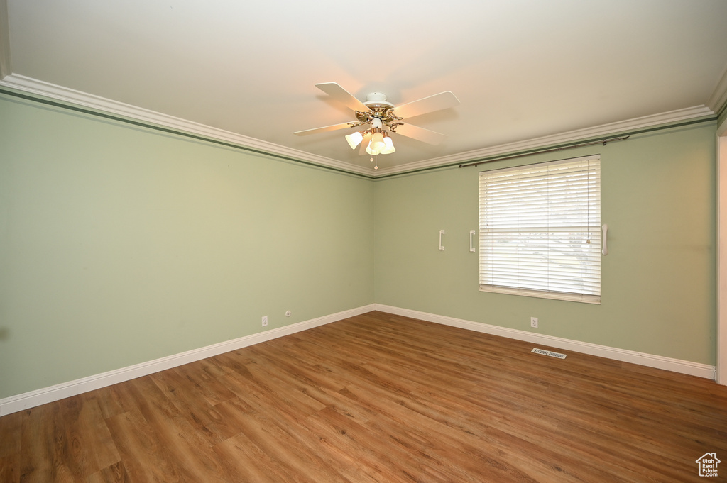 Unfurnished room with ceiling fan, dark wood-type flooring, and ornamental molding
