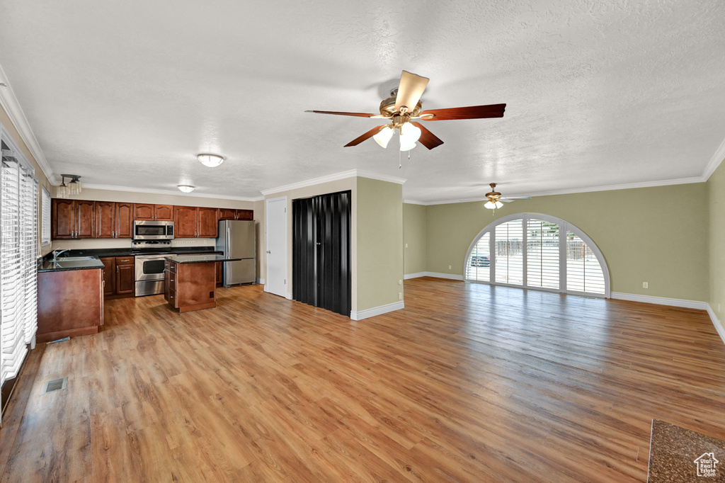 Kitchen with a center island, light hardwood / wood-style flooring, ornamental molding, appliances with stainless steel finishes, and ceiling fan