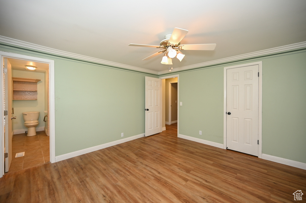 Unfurnished bedroom featuring a closet, ceiling fan, connected bathroom, light hardwood / wood-style floors, and ornamental molding