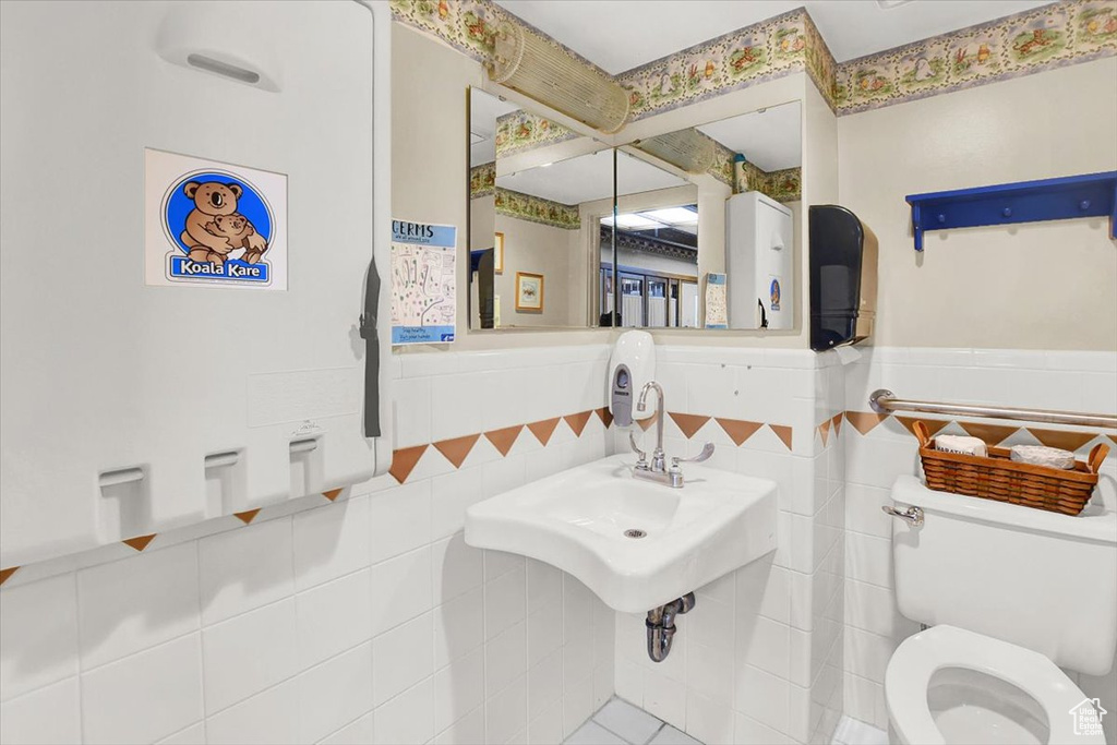 Bathroom featuring tile floors, tile walls, sink, and toilet