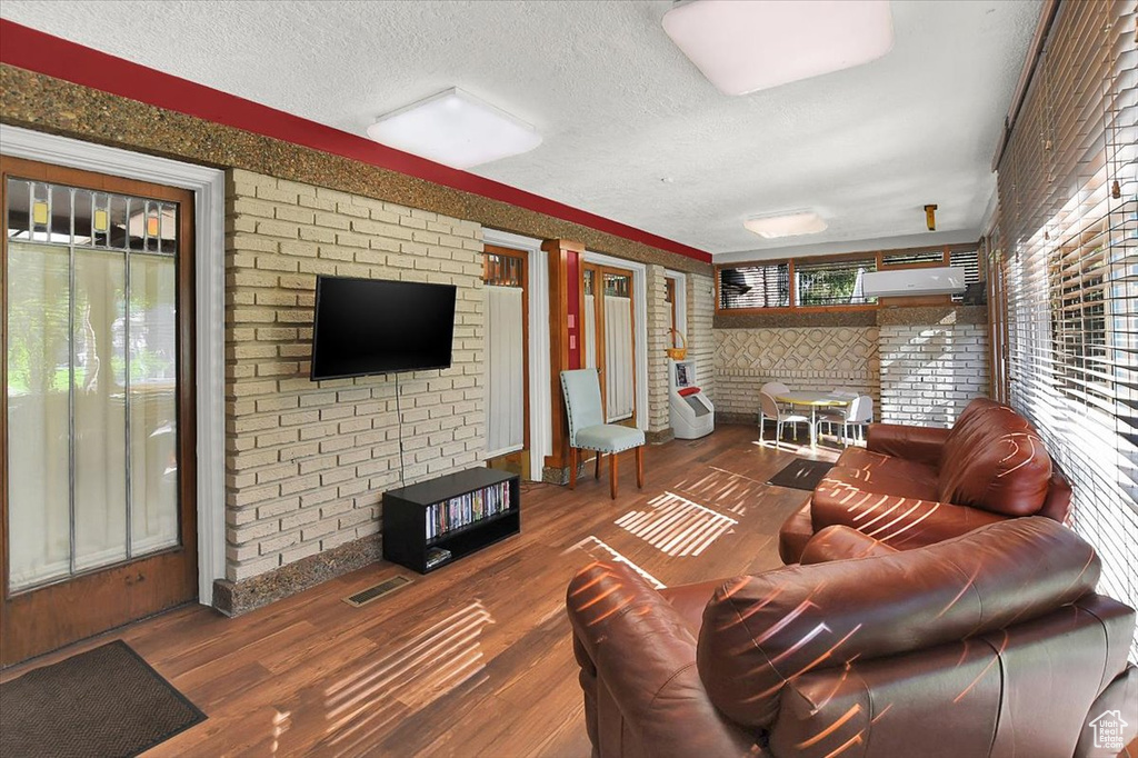 Living room with brick wall, dark hardwood / wood-style flooring, and a textured ceiling