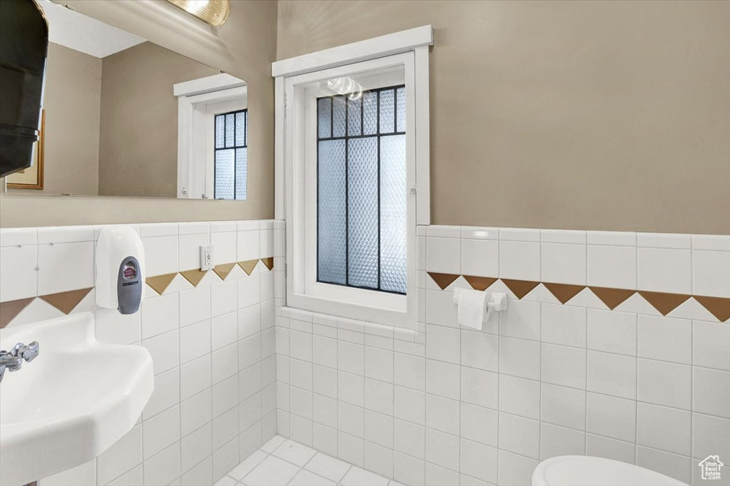 Bathroom featuring sink, tile walls, and toilet