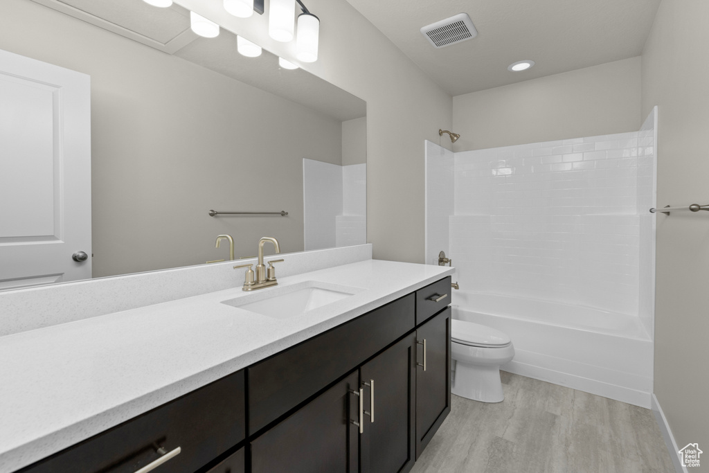 Full bathroom featuring shower / washtub combination, wood-type flooring, toilet, and large vanity