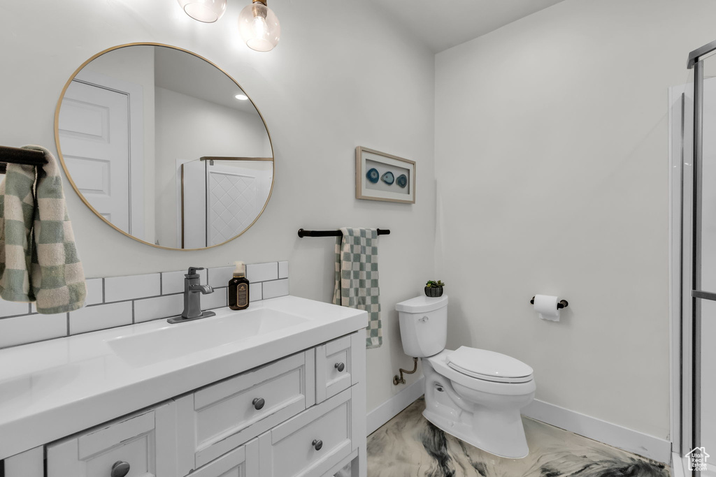 Bathroom featuring vanity, tasteful backsplash, and toilet