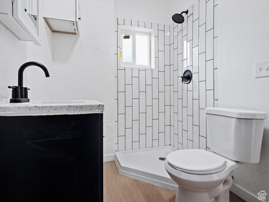 Bathroom featuring vanity, hardwood / wood-style floors, tiled shower, and toilet