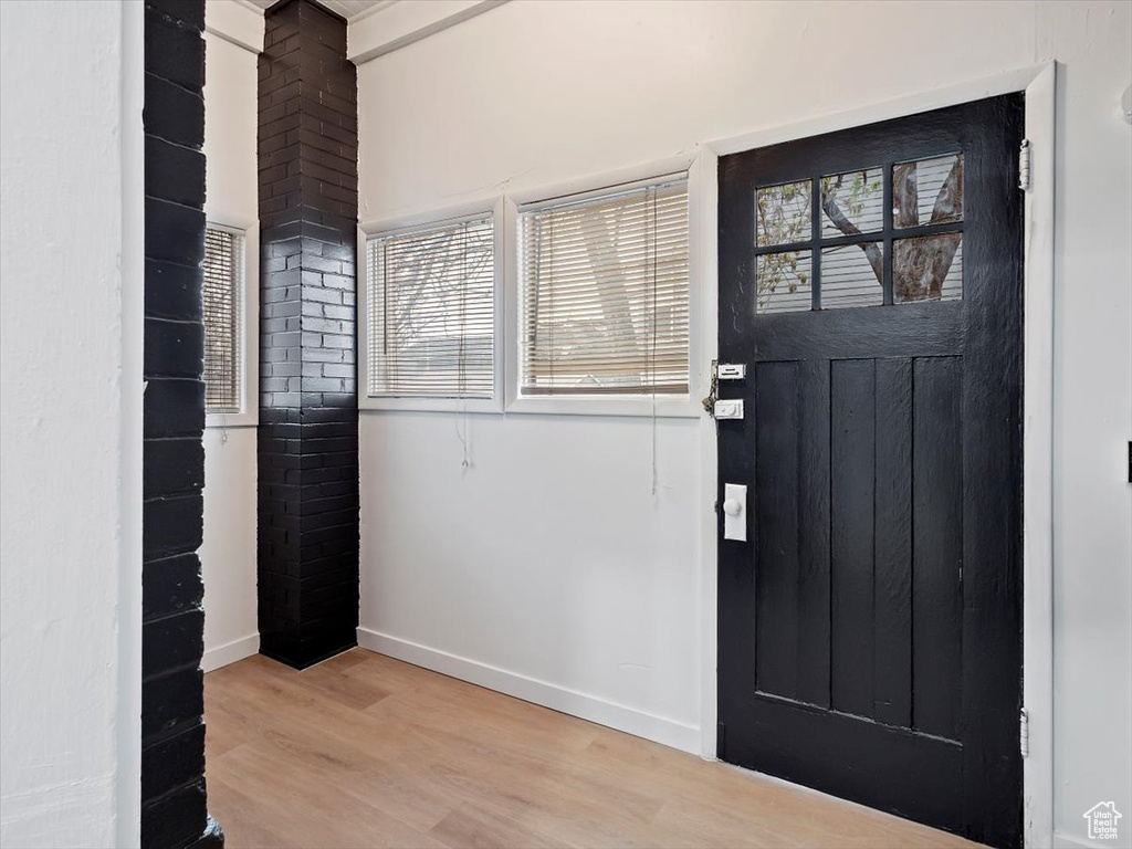 Foyer featuring brick wall and light hardwood / wood-style floors