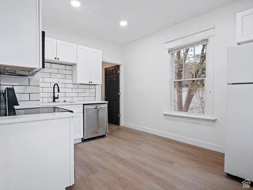 Kitchen with white refrigerator, light hardwood / wood-style floors, dishwasher, and white cabinets
