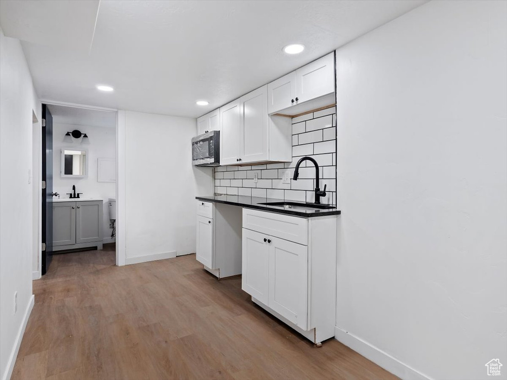 Kitchen with sink, light hardwood / wood-style floors, tasteful backsplash, and white cabinetry