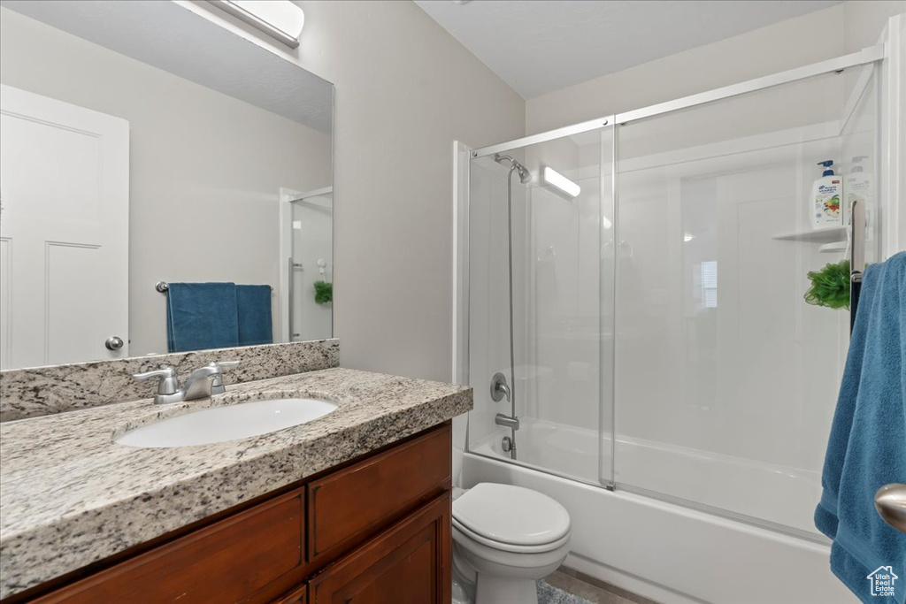Full bathroom with enclosed tub / shower combo, toilet, and oversized vanity
