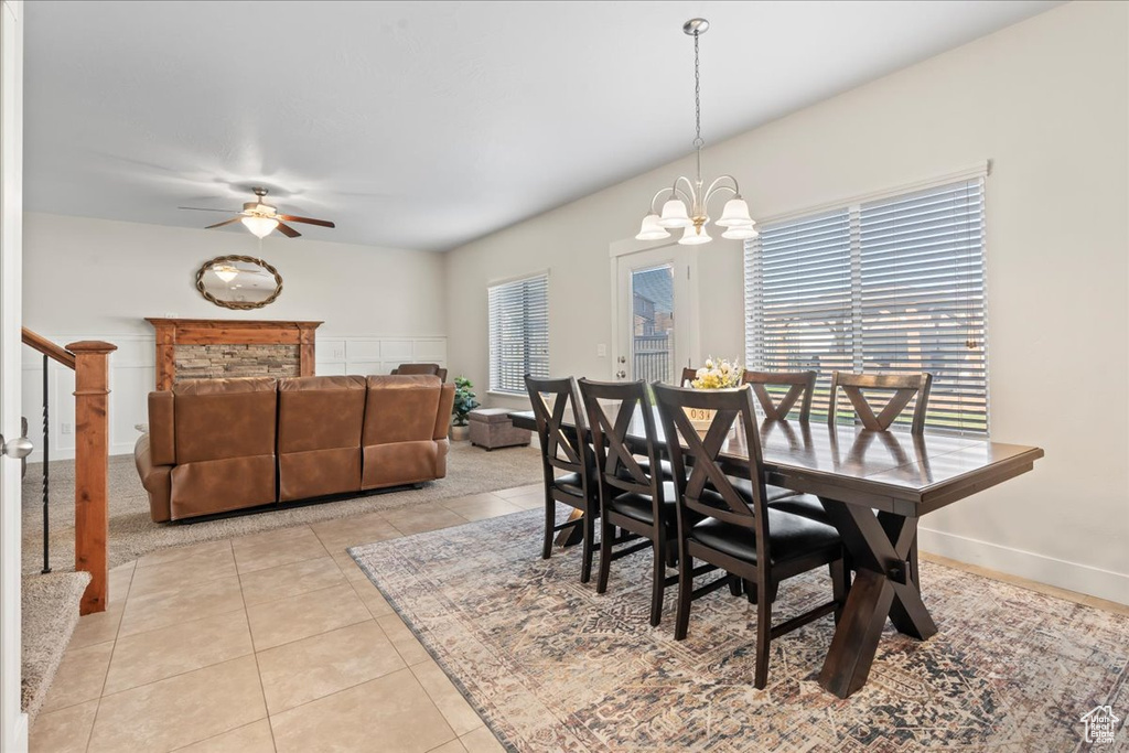 Tiled dining area featuring plenty of natural light and ceiling fan with notable chandelier