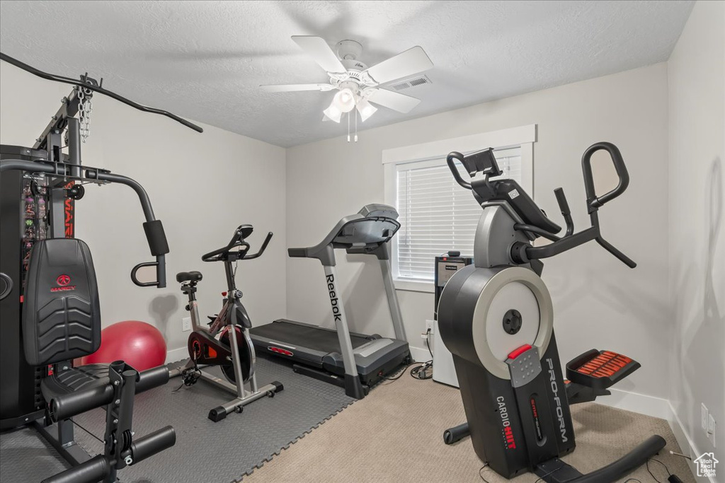 Workout area featuring light carpet, ceiling fan, and a textured ceiling