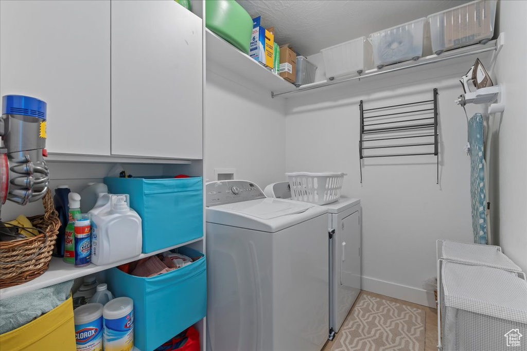 Laundry area featuring cabinets, light tile flooring, and washer and clothes dryer
