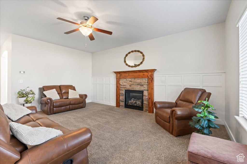 Living room with ceiling fan, light carpet, and a stone fireplace
