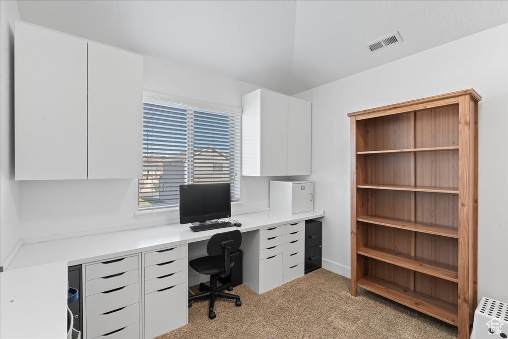 Carpeted home office with built in desk and radiator heating unit