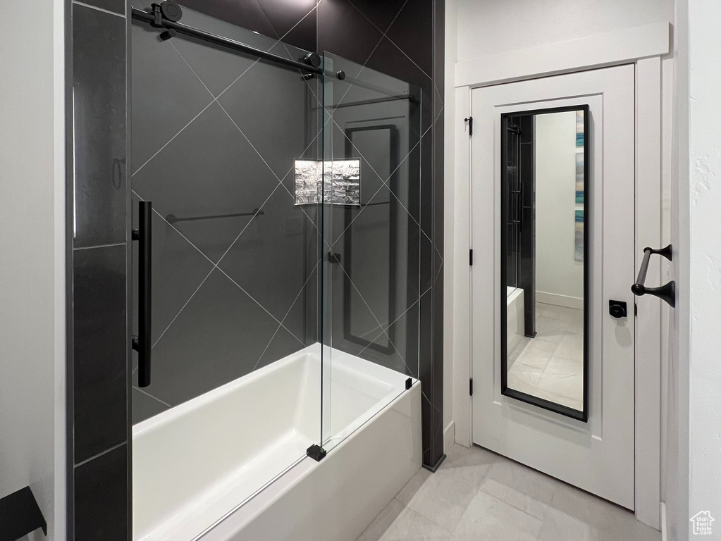 Bathroom featuring shower / bath combination with glass door and tile flooring