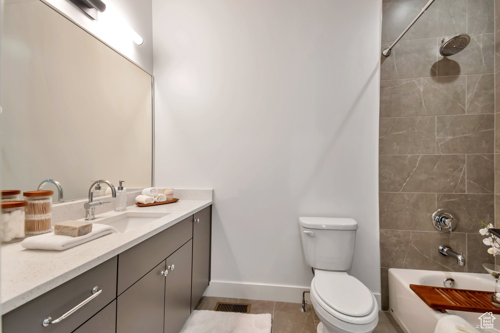 Full bathroom with tiled shower / bath, vanity, toilet, and tile floors