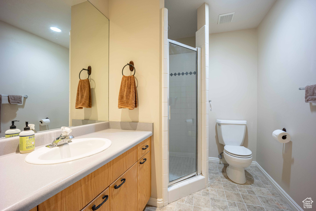 Bathroom with walk in shower, toilet, tile flooring, and vanity