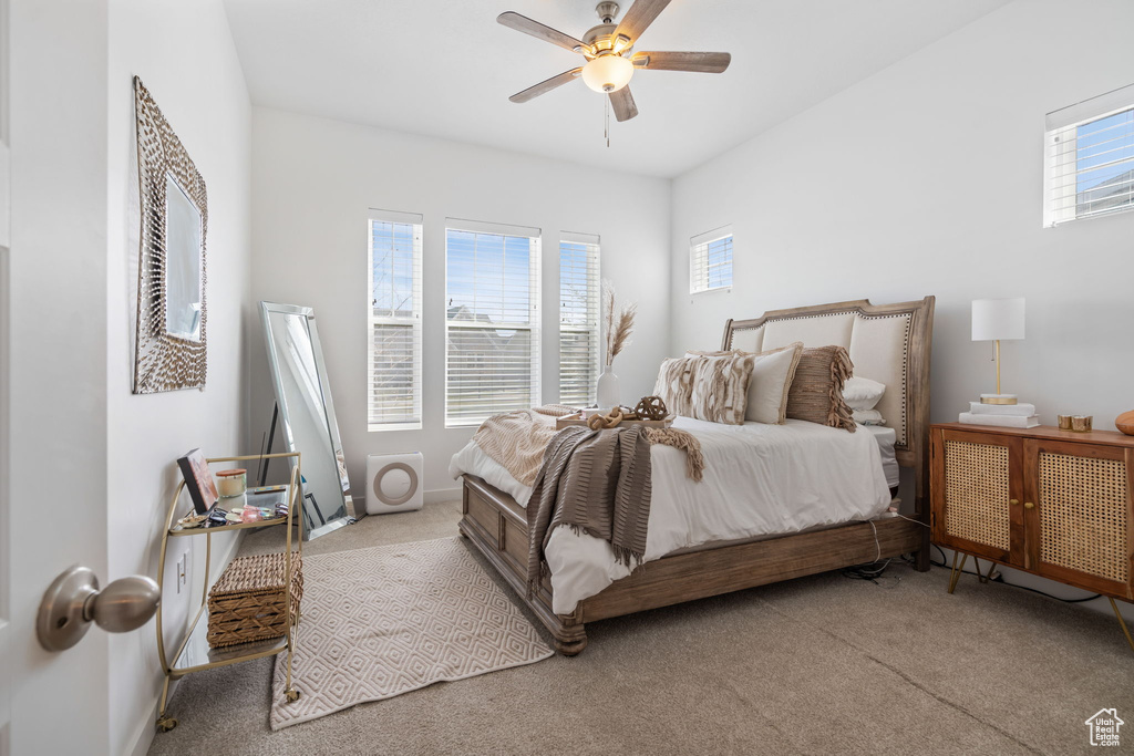Bedroom featuring light carpet, multiple windows, and ceiling fan