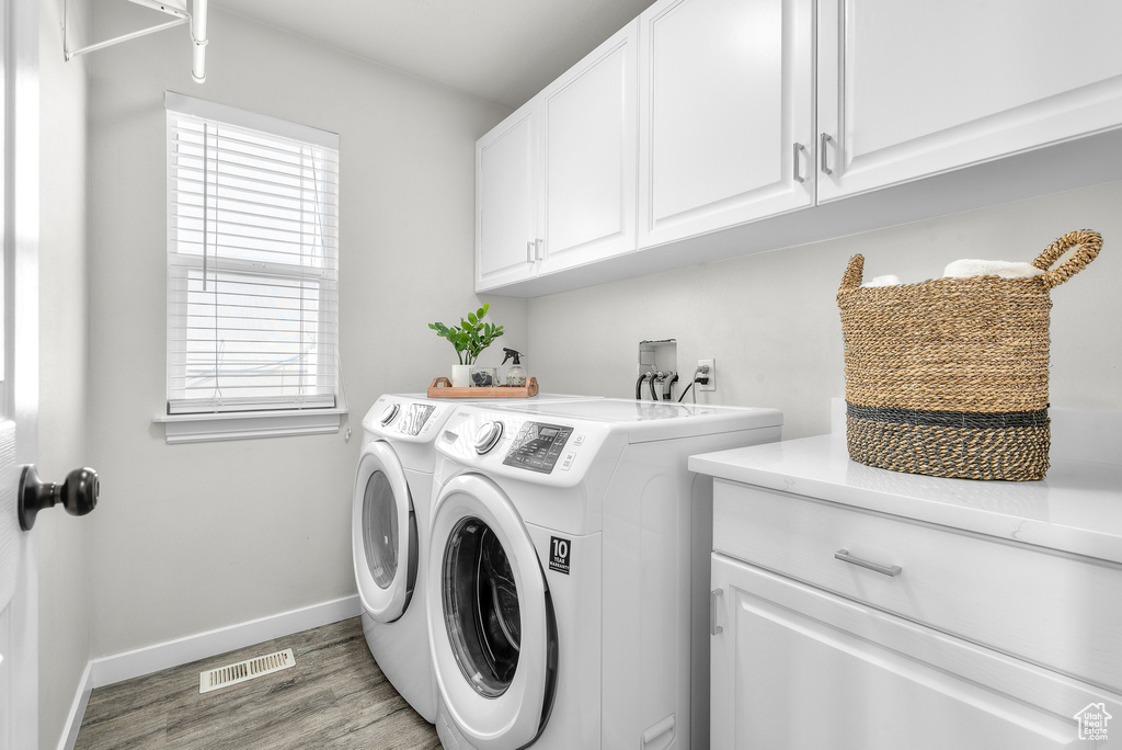 Clothes washing area with washer hookup, light hardwood / wood-style floors, cabinets, and washer and dryer
