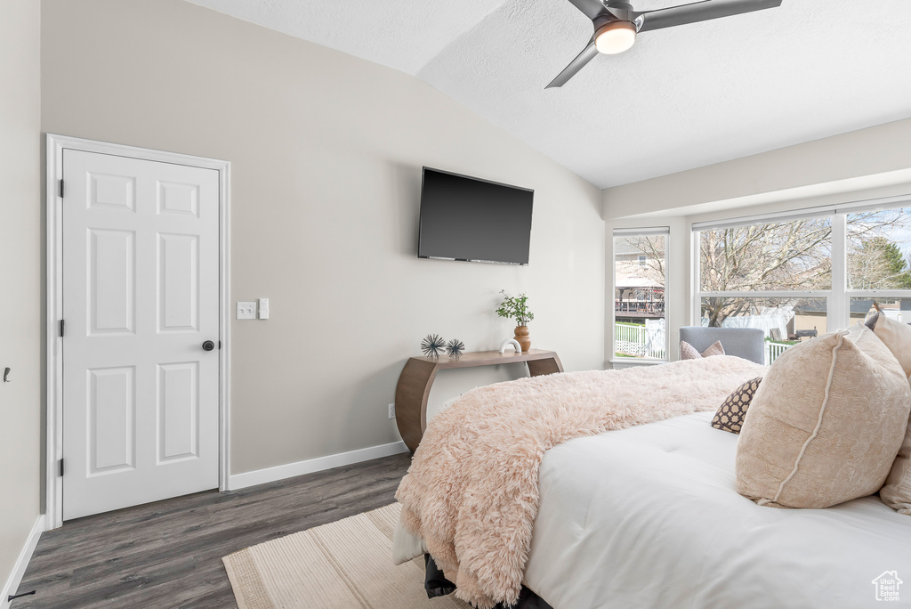 Bedroom with dark hardwood / wood-style flooring, ceiling fan, and vaulted ceiling