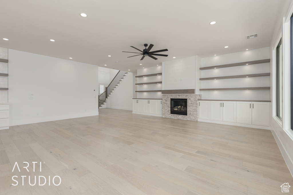 Unfurnished living room featuring a fireplace, ceiling fan, and light hardwood / wood-style floors