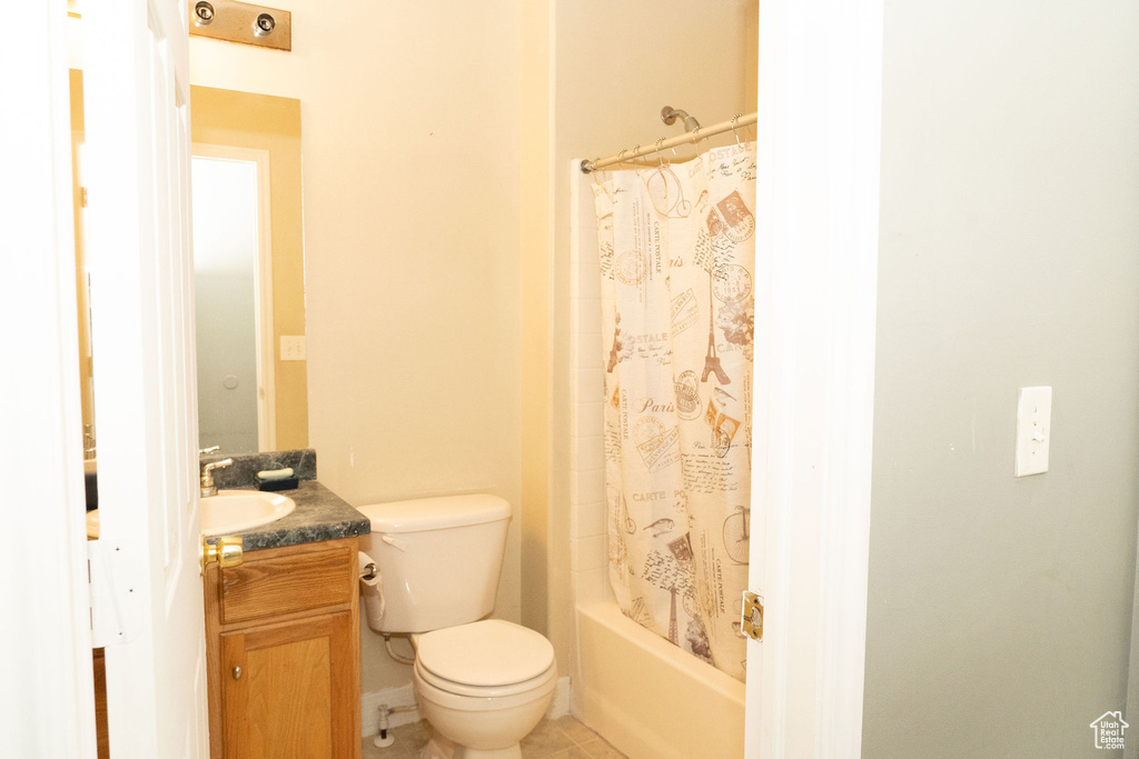 Full bathroom featuring tile floors, toilet, large vanity, and shower / bath combo with shower curtain
