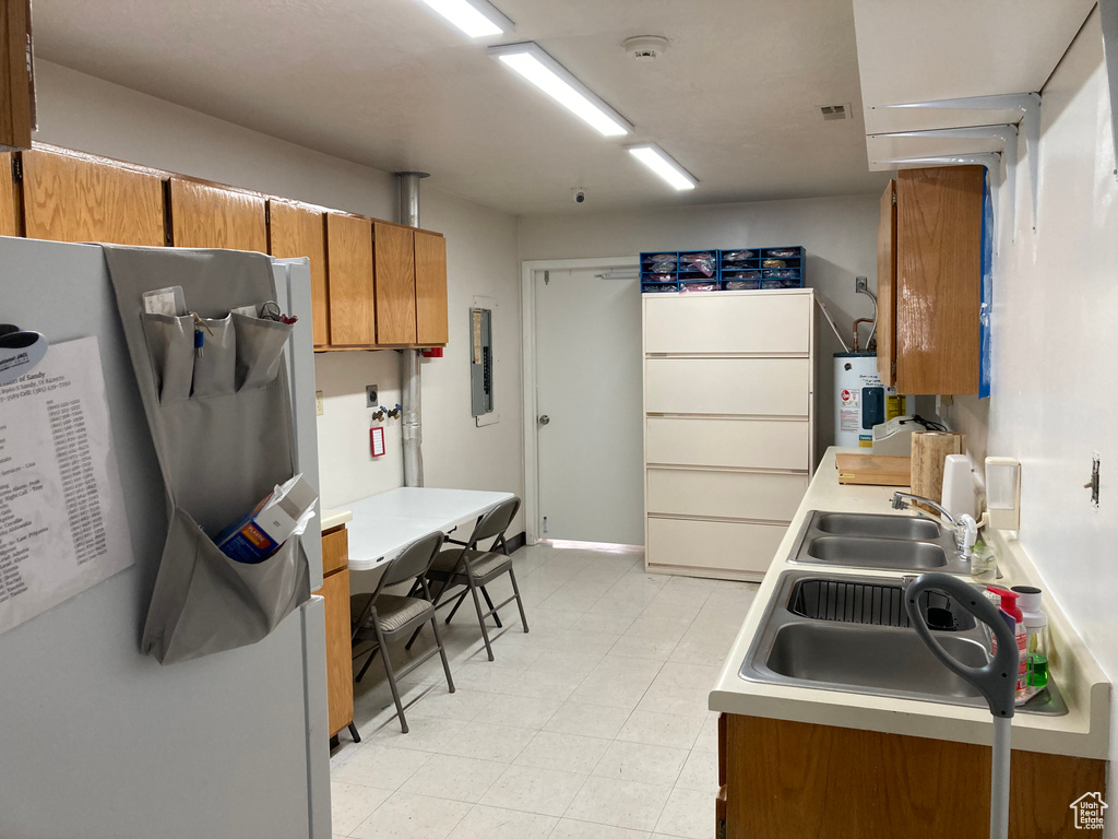 Kitchen with sink, water heater, light tile flooring, and fridge