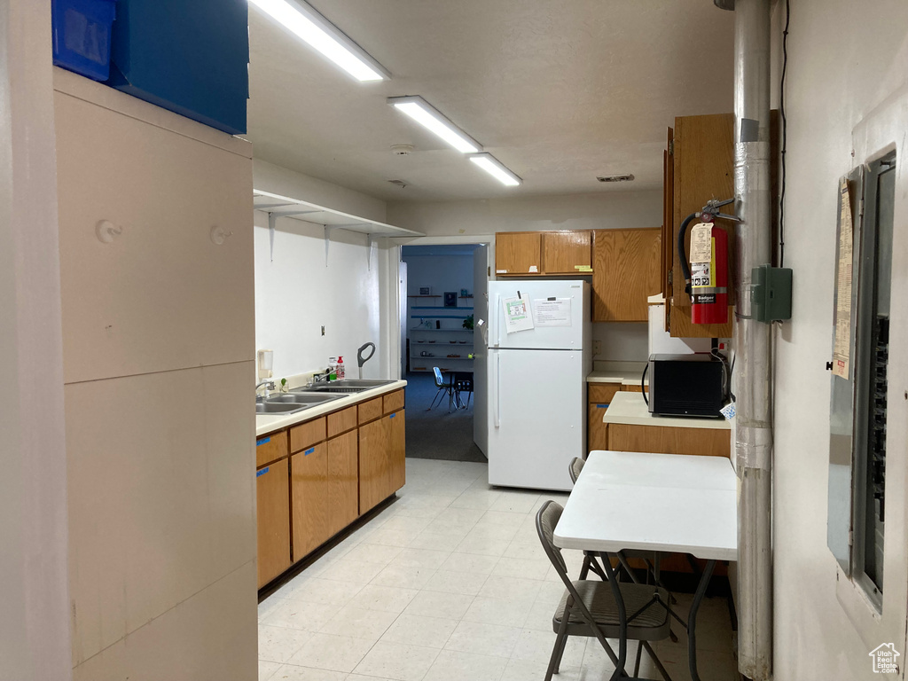Kitchen featuring white refrigerator and light tile floors