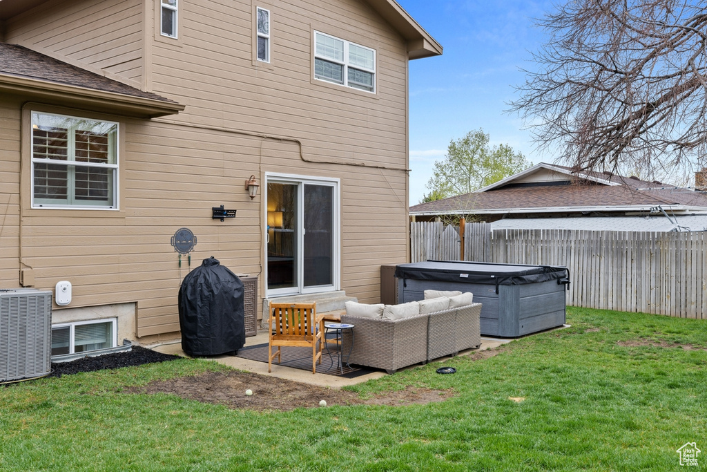 Rear view of house featuring an outdoor living space, a hot tub, a yard, and central AC unit