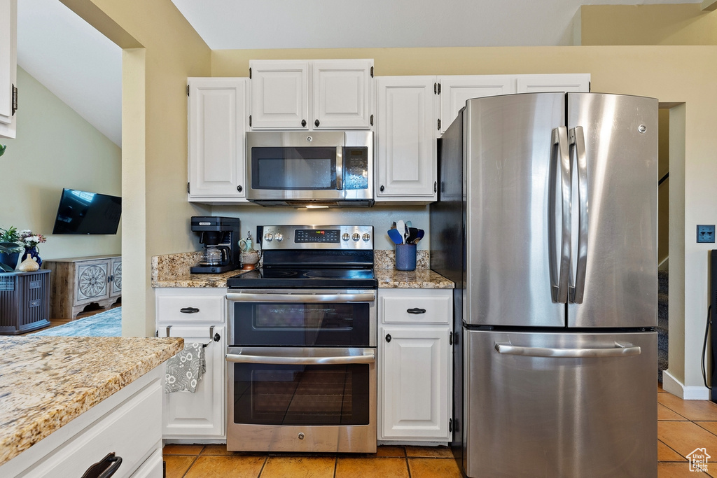 Kitchen featuring appliances with stainless steel finishes, light tile floors, and white cabinetry