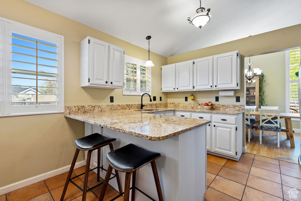 Kitchen with white cabinets, kitchen peninsula, and light tile floors