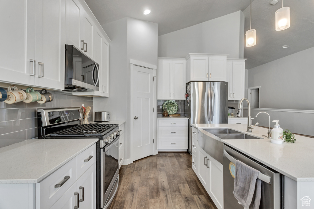 Kitchen with appliances with stainless steel finishes, lofted ceiling, tasteful backsplash, and white cabinetry