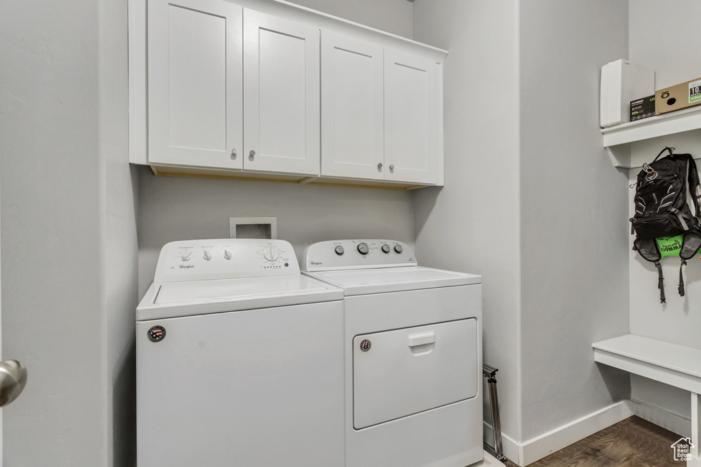 Laundry area featuring cabinets, washing machine and clothes dryer, and dark hardwood / wood-style floors